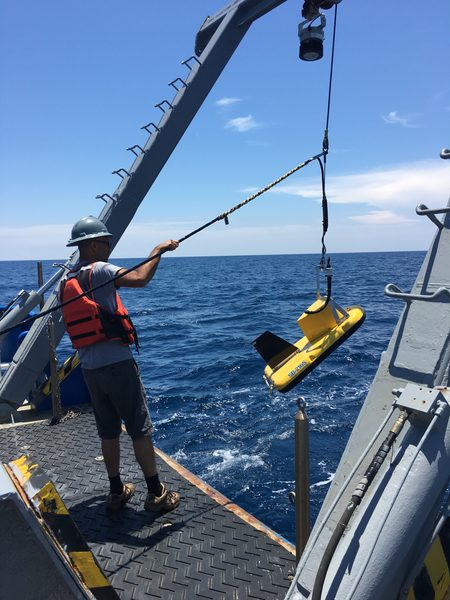Launching the towfish over the stern; the shelf below is the submerged half of the continuum.